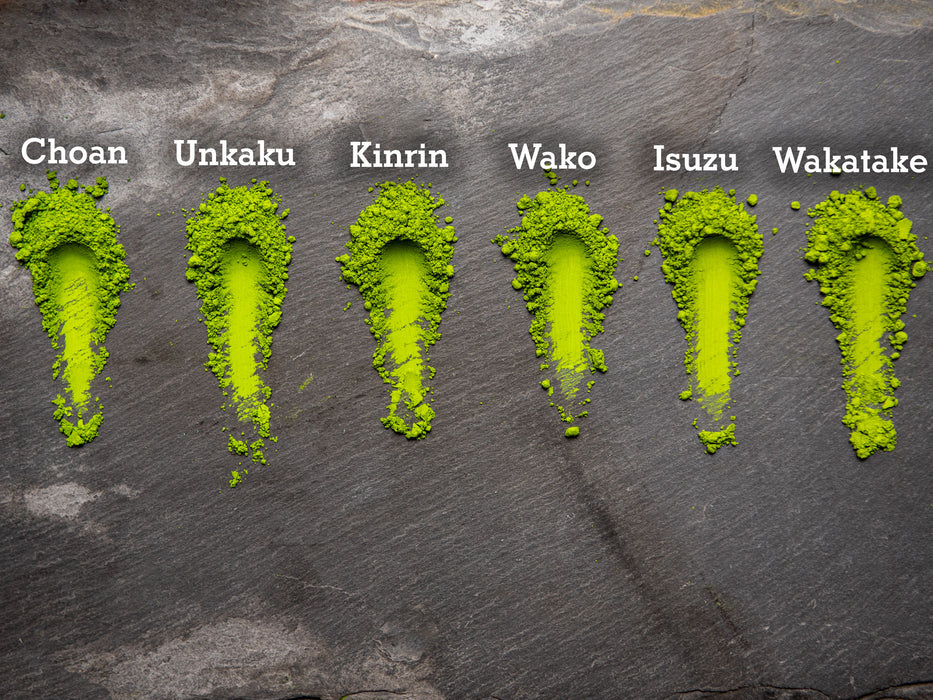 Six different grades of Marukyu Koyamaen matcha green tea powder labeled on a dark stone surface